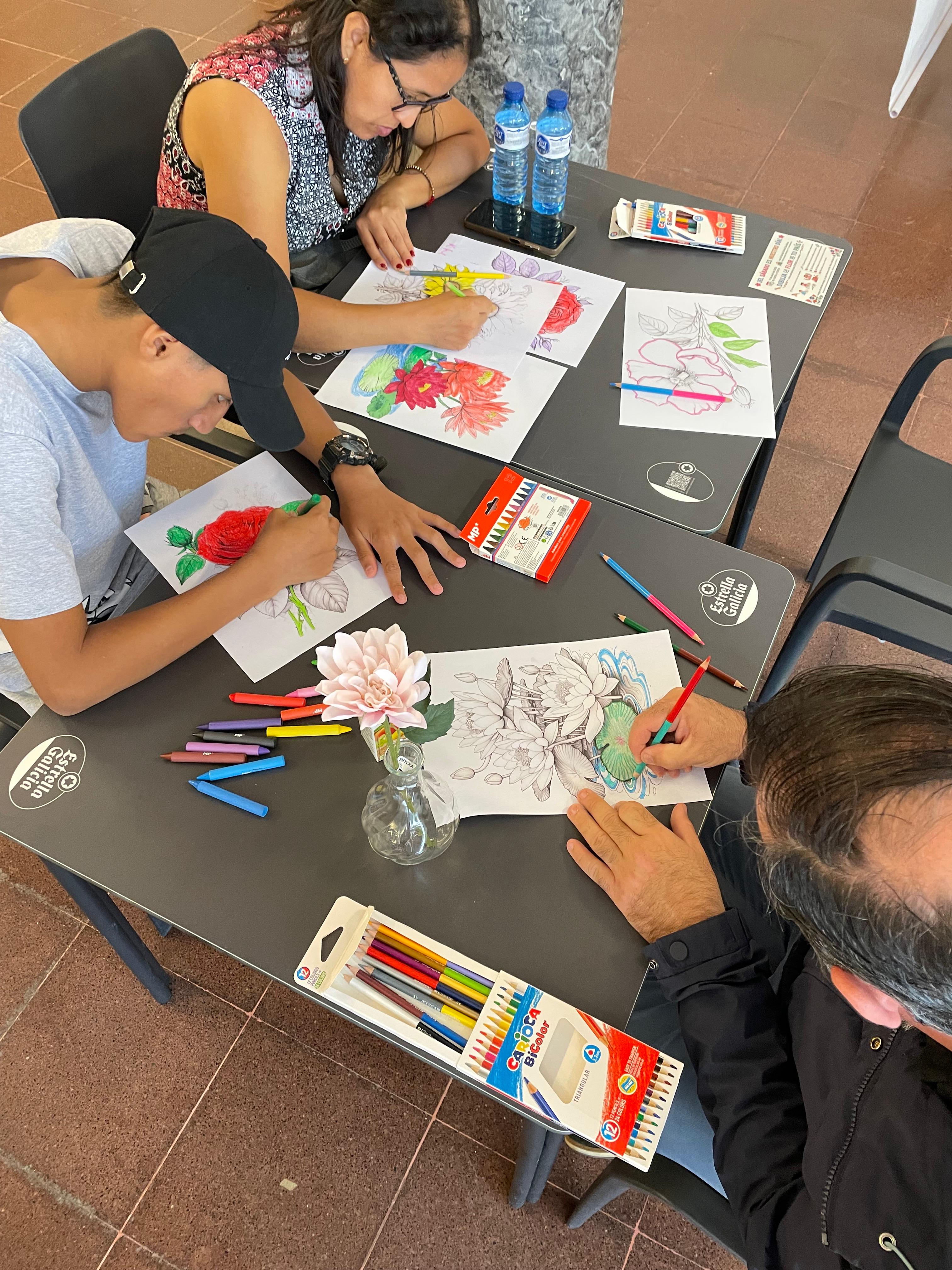 Familias dibujando flores juntas — adultos y niños compartiendo la mesa
